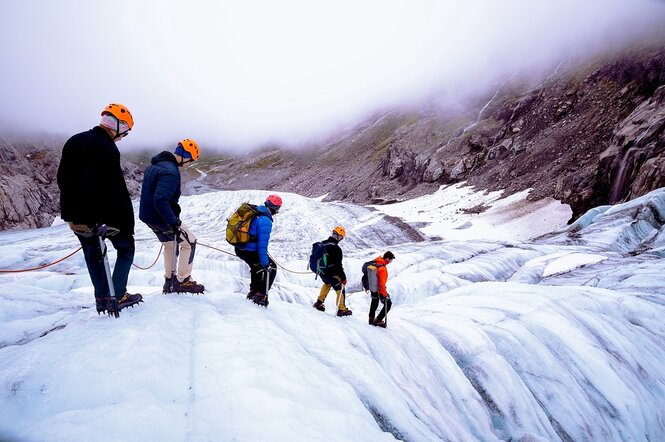 Menschen stehen auf einem gletscher und halten sich an einem Seil fest