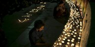 Menschen sitzen vor Kerzen, um der Opfer einer Messerattacke zu gedenken