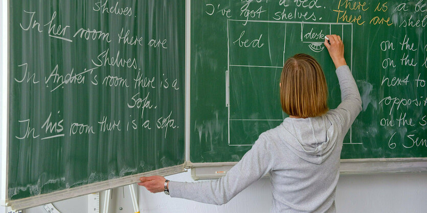 Eine Englisch-Lehrerin schreibt Unterrichtsinhalte an die Tafel