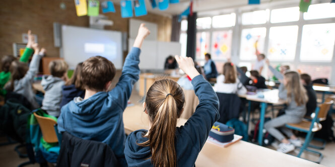 Schüler:innen in einem Klassenraum melden sich