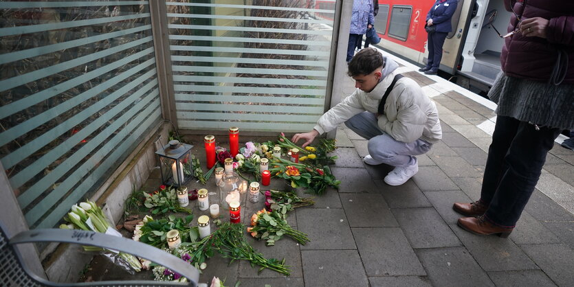 Ein Freund des getöteten 19-Jährigen legt Blumen am Bahngleis ab