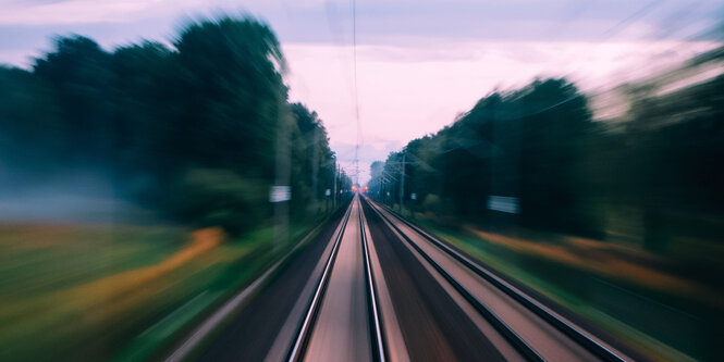 Bahngleise aus der Perspektive eines Lokführers. Die Umgebung ist verzerrt und suggeriert hohe Geschwindigkeit.