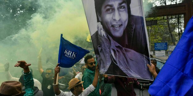 Fans tragen ein Porträt von Sharoukh Khan durch die Straßen und feirern mit bunten Rauchbomben