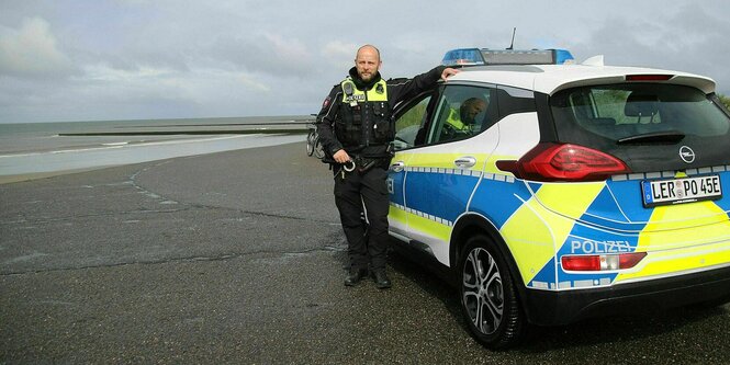 Ein Polizeiauto steht an einem Strand.