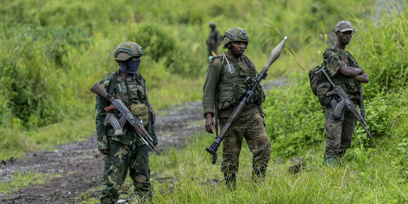 Uniformierte Soldaten stehen im Gras an einer Straße