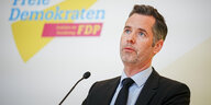 Ein Mann, FDP-Fraktionschef Christian Dürr, steht nachdenklich hinter einem Mikrofon
