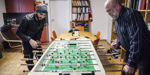 Ein junger und ein alter Mann spielen Kicker