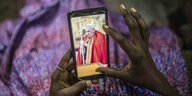 Eine Frau schaut sich ein Foto von Papst Franziskus auf ihrem Smartphone an