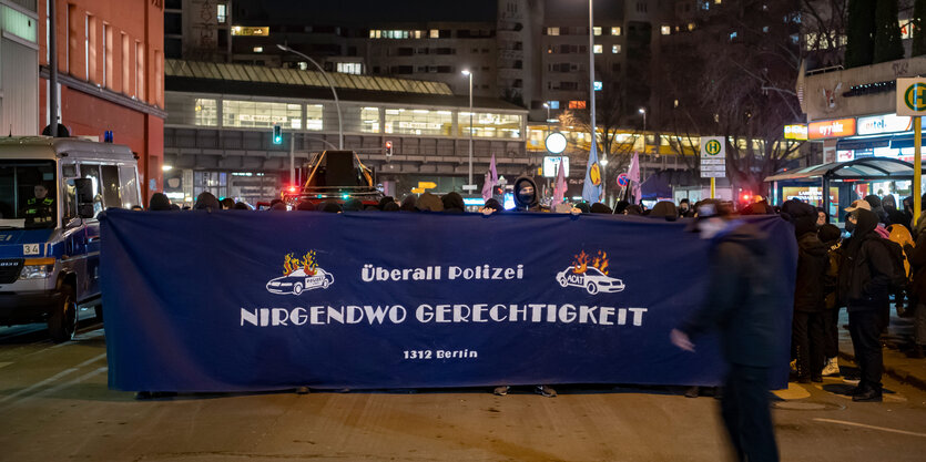 Aktivist*innen halten bei einer Demo am Kotti ein Plakat, auf dem steht: "Überall Polizei - nirgendwo Gerechtigkeit. 1312 Berlin"