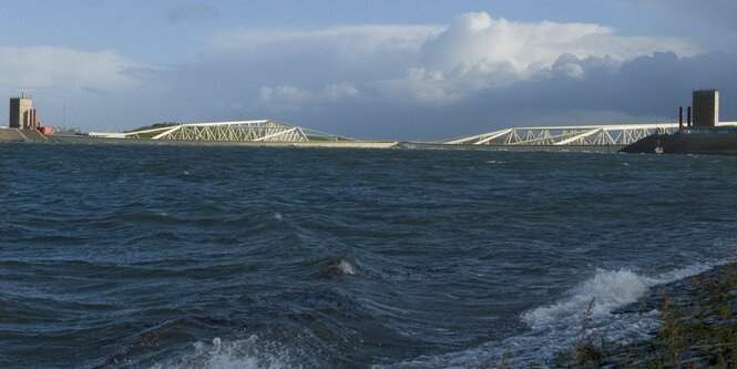 Hohe Welle und im Hintergrund ein Sturmflutwehr