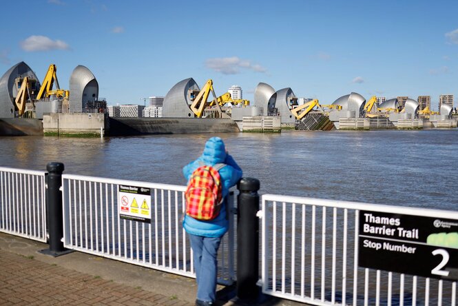 ein Mensch schaut von einer Brücke auf eine aufwendige Flutsperre