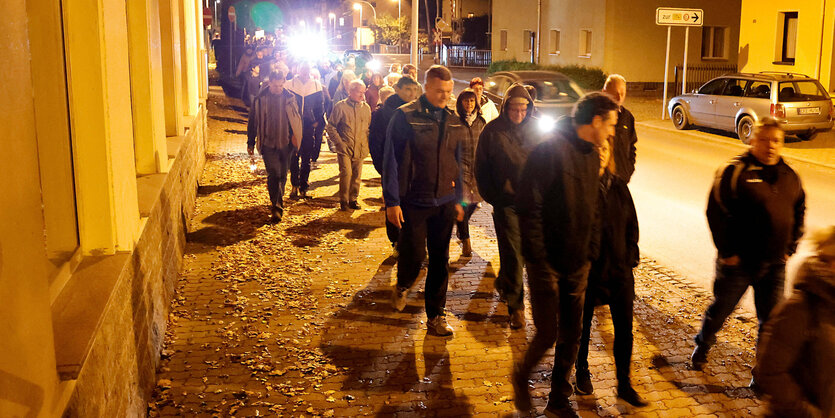 Menschen gehen nachts über eine Straße