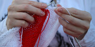 Frauenhände stricken weiß-rot-weiß