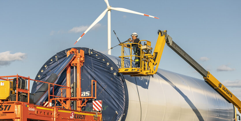 Vor der Montage des Windradturms wird ein Turmsegment auf dem Schwerlasttransporter von Staub und Schmutz gereinigt,