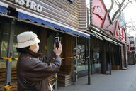 Eine Frau schießt Fotos der Sanlitun Bar Street in Peking