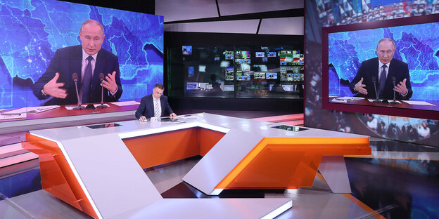 Ein Fernsehstudio, im Hintergrund Putin auf großen Bildschirmen