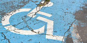 Abblätterndes Rollstuhl-Symbol auf Parkplatzfläche