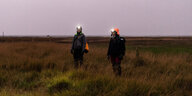 Zwei Menschen mit Stirnlampen stehen in den Salzwiesen an der Küste der Nordseeinsel Spiekeroog