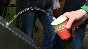 Aus einem Wasserspender kommt ein Strahl, der mit einem Becher aufgefangen wird, auf dem steht: das reinste Vergnügen