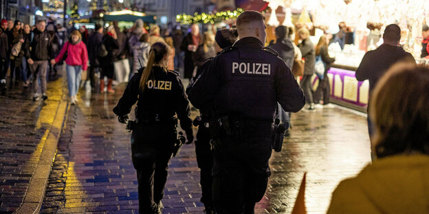 Polizisten laufen Streife über einen Weihnachtsmarkt