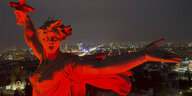 Die riesige Statur "Mutter der Heimat" in Volgograd ist in rotes Licht getaucht, dahinter glitzert die Großstadt