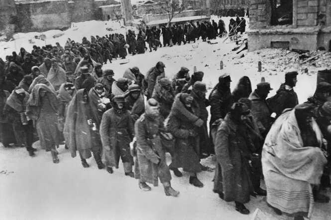 Ein Zug von Kriegsgefangenen gebückt im Schnee