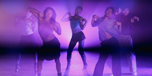 Fünf Performer*innen stehen in Posen in einem Raum, von hinten angestrahlt in einem dunklen Pink