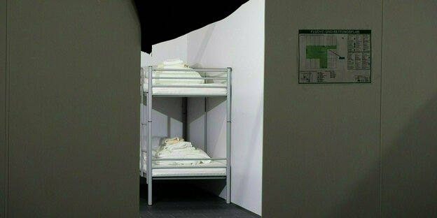 Durch eine Tür ist ein Doppelstockbett mit weisser Wäsche und Handtüchern zu sehen