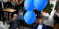 Alexander Gauland und Björn Höcke sitzen in einem Lokal - über ihnen schweben blaue AfD-Luftballons