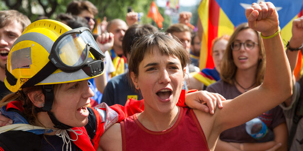 Mehrere Frauen, darunter eine in Feuerwehrkleidung, auf einer Demo, im Hintergrund die katalanische Flagge