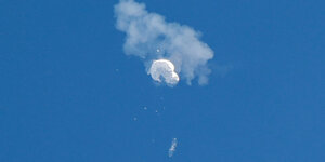 Weißer geplatzter Ballon mit einer Rauchwolke an blauem Himmel