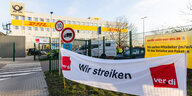Ein Banner mit der Aufschrift "Wir streiken" der Gewerkschaft Ver.di hängt vor einem Gebäude des Paketdienstleisters DHL