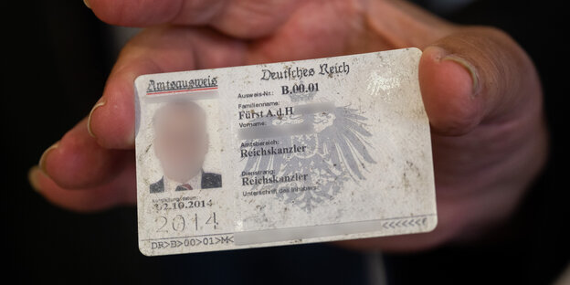 Eine Hand hält einen Fantasie-Ausweis, dessen Besitzer sich selbst zum "Reichskanzler" gemacht hat