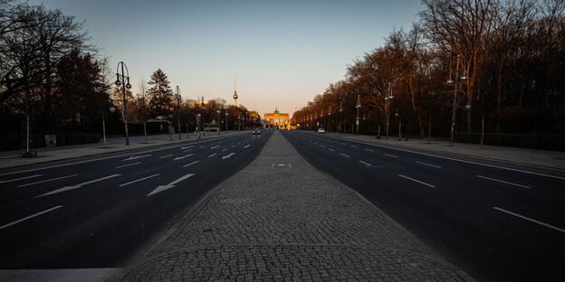 Leere Straße in Berlin bei Tage, das Brandenburger Tor leuchtet