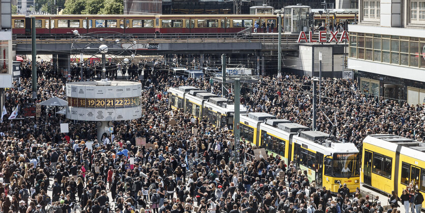 Eine gelbe Straßenbahn zwischen einer Menschenmenge am Alexanderplatz