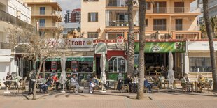 Deutsche Touristen sitzen vor der Bar Zur Krone an der Playa de Palma auf Mallorca.