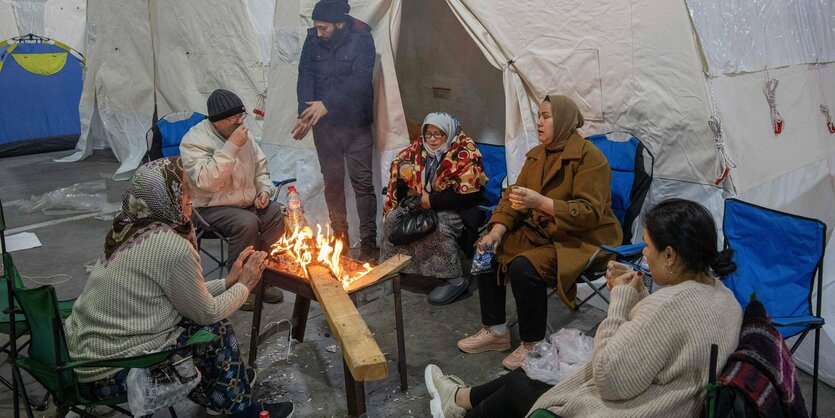 Menschen sitzen vor einem Zelt an einem Feuer