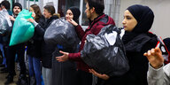 Mitglieder dertürkischen Gemeinde stehen aufgereiht, um große Plastiksäcke mit warmer Kleidung weiterzureichen