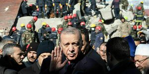Recep Tayyip Erdogan steht vor einem eingestürzten Gebäude und winkt in die Kameras