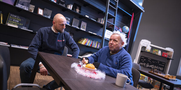 Besucher der Wärmestube, sitzt in der Wärmestube im Humboldt-Forum mit einem Mitarbeiter der Johanniter zusammen