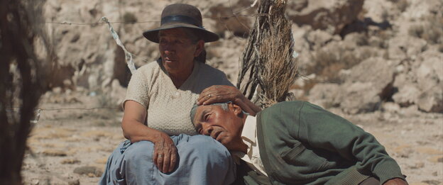 Zwei alte Menschen sitzen vor steiniger, karger Landschaft