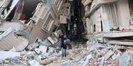 Zwischen zwei von Erdbeben zerstörten Häusern läuft ein Mann entlang