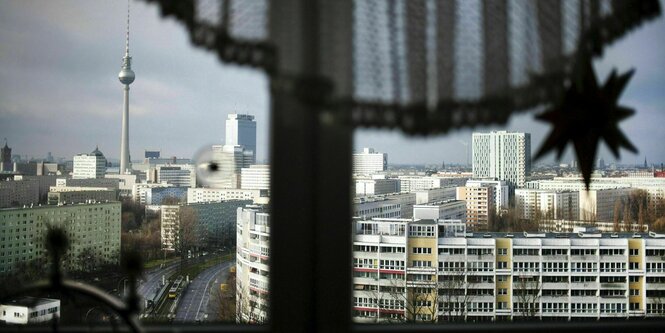 Blick aus einem Fenster, vor dem ein schwarzer Vorhang das halbe Fenster verdeckt - zu sehen ist der Platz der Vereinten Nationen, im Hintergrund der Fernsehturm