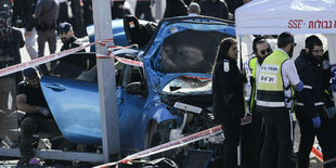 Bil eine szerstörten blauen Autos, drumherum Rettungskräfte