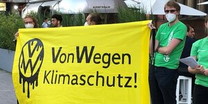 Greenpeace-Aktivisten mit gelbem Banner Von Wegen Klimaschutz