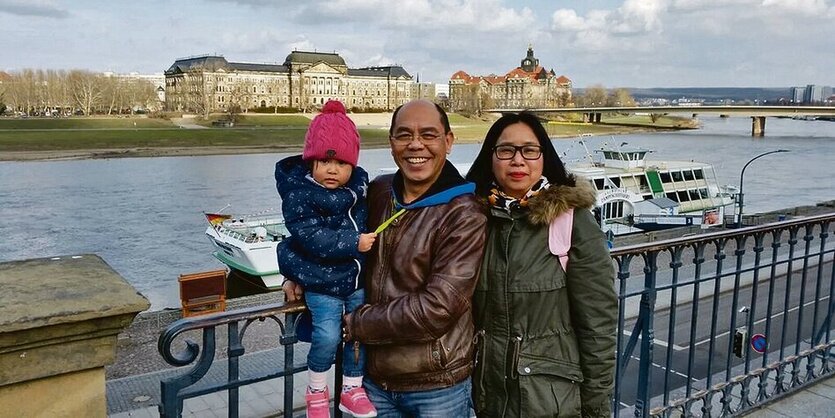 Vater, Mutter, Kind auf einer Brücke über einem Fluss