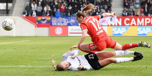 Zwei Spielerinnen gehen im Zweikampf zu Boden