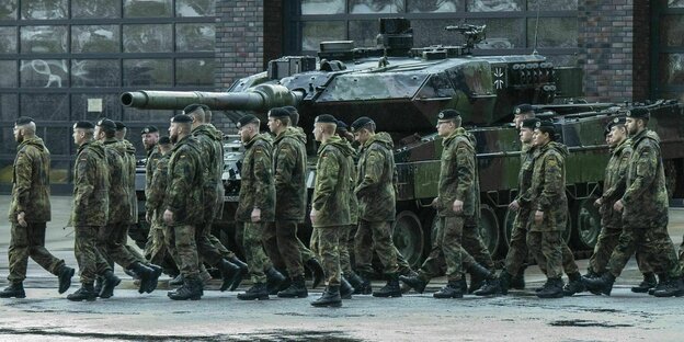 uniformierte Soldaten neben einem Panzer vor Halle