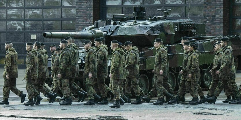 uniformierte Soldaten neben einem Panzer vor Halle