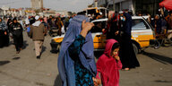 Mehrer Personen auf einer Straße in Afghanistan, im Vordergrund eine Frau mit Kind